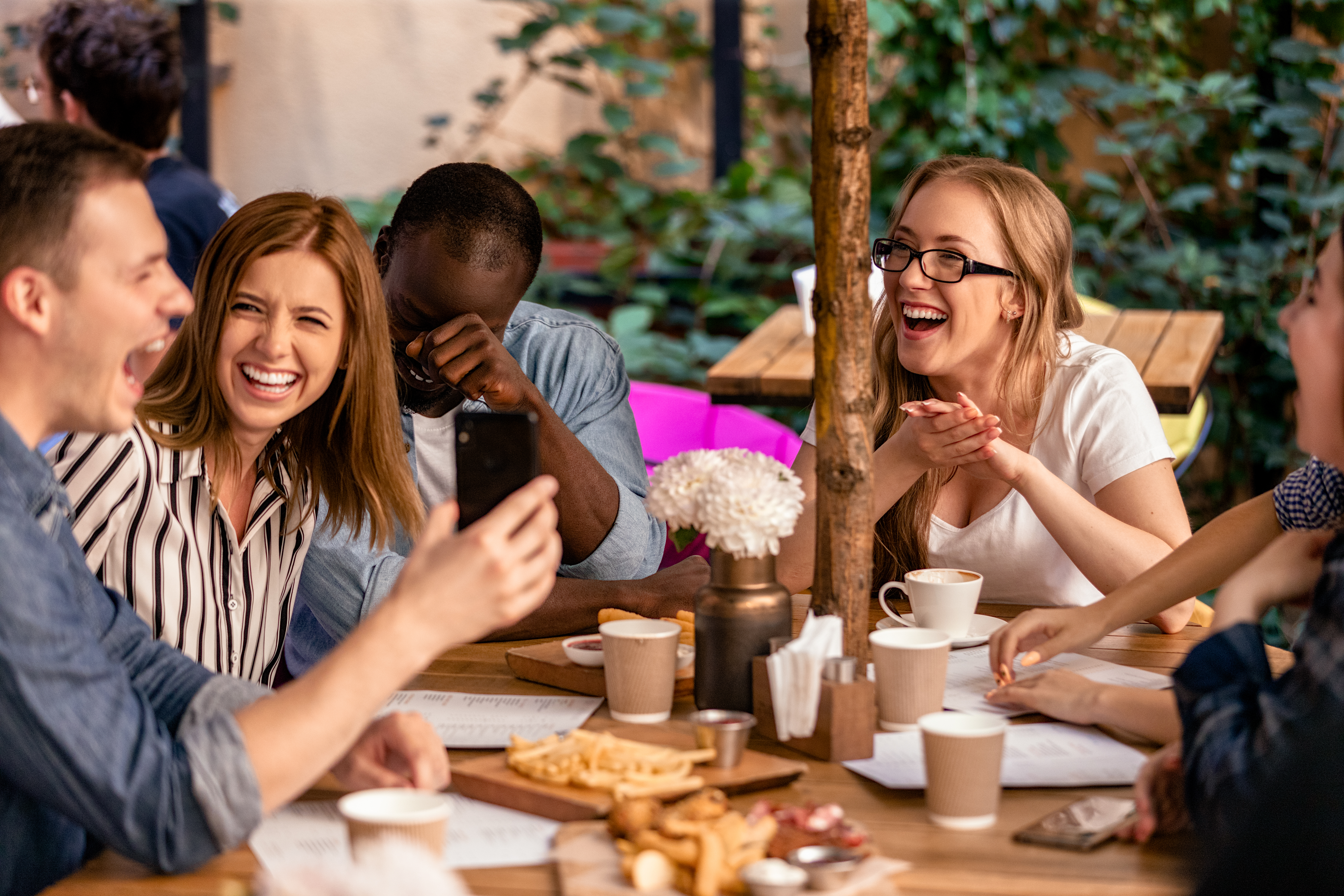 Amis qui rient en terrasse de restaurant, clients fidèles et heureux