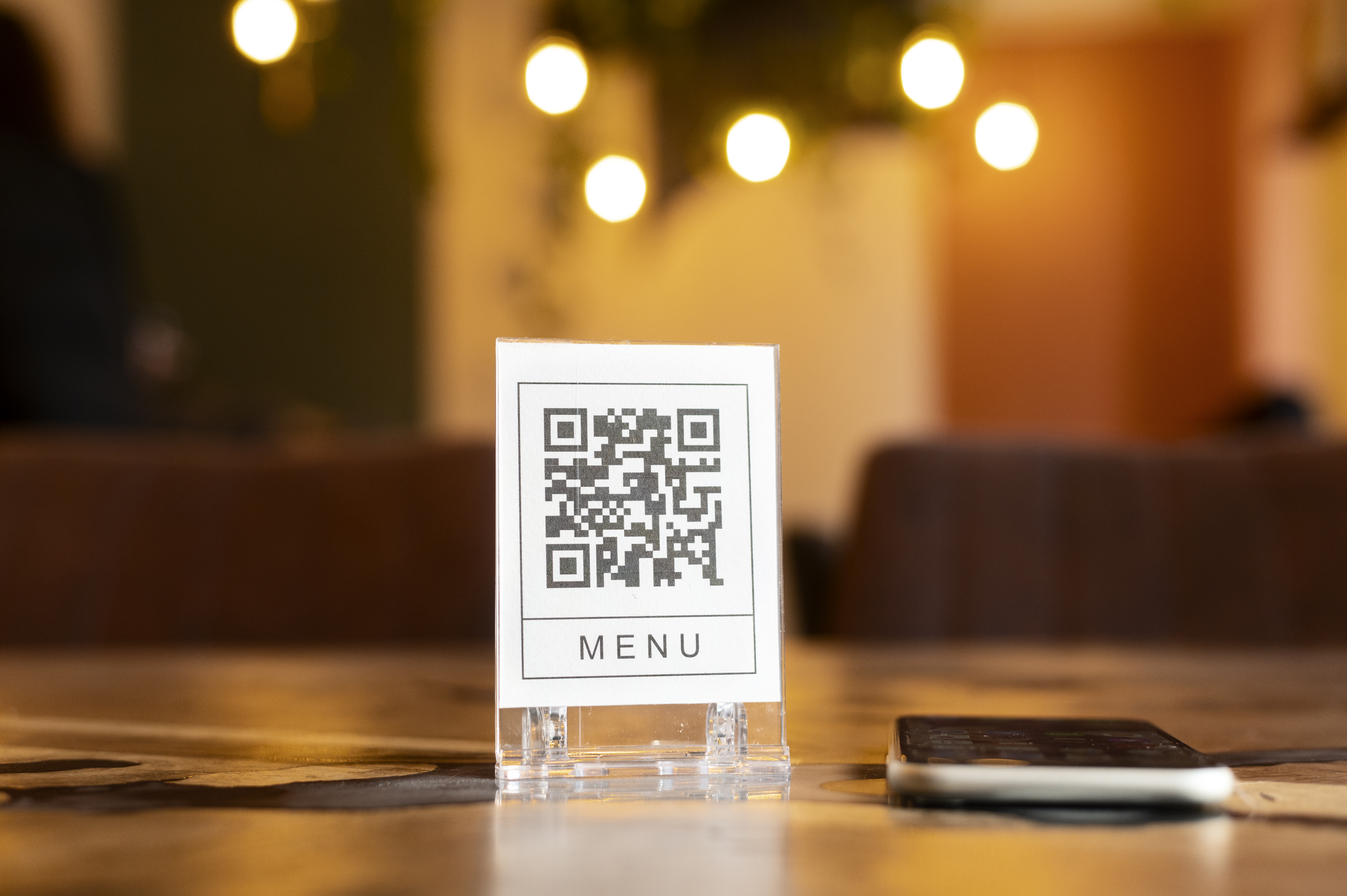 QR code menu posé sur une table de restaurant avec ambiance chaleureuse